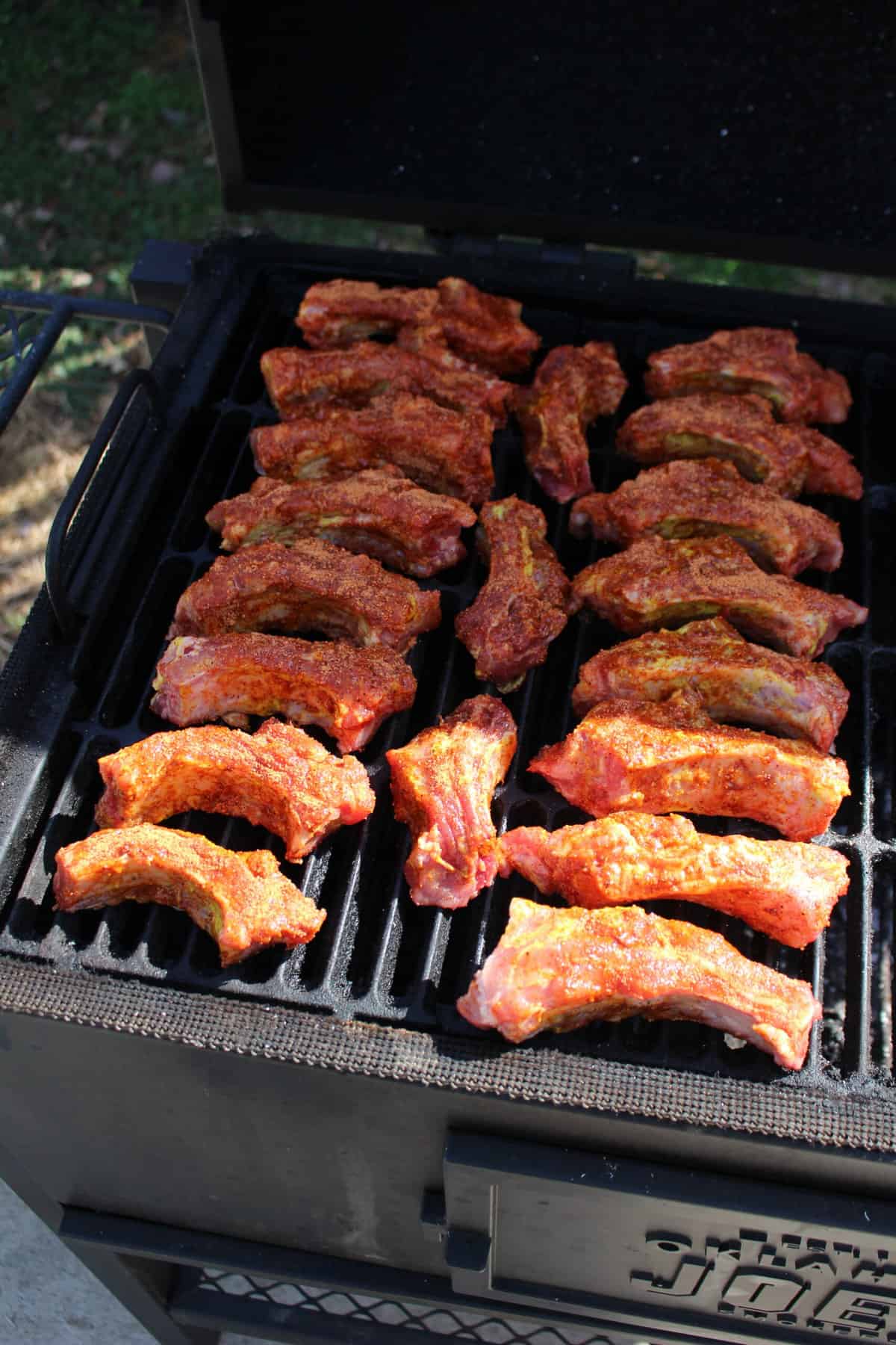Individuals ribs smoking over indirect heat.