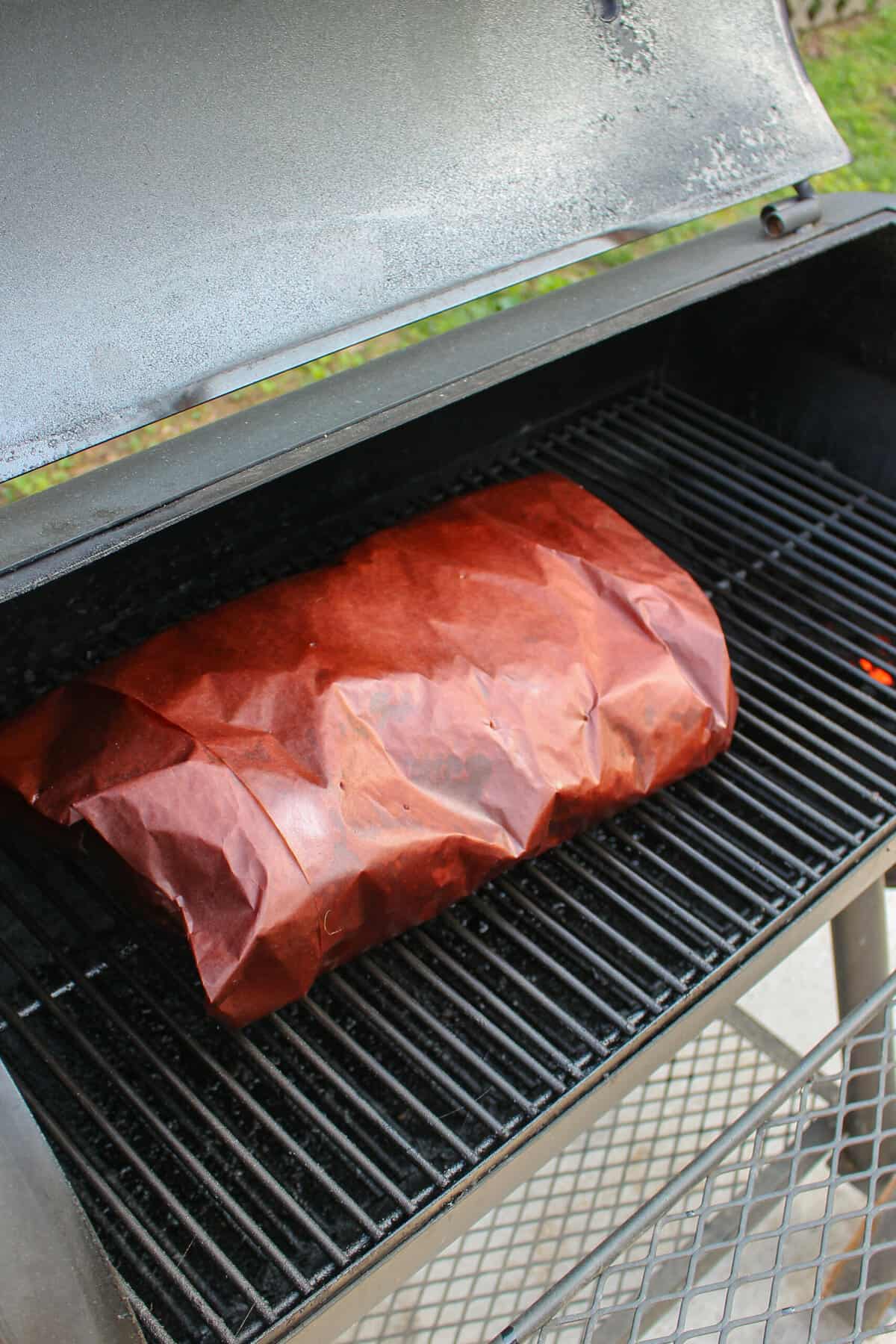 The wrapped brisket on the smoker.
