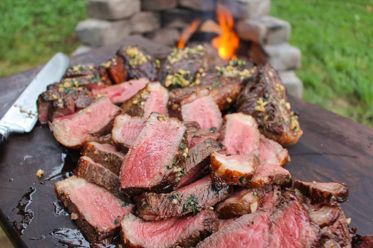 Sliced and served steak sitting on a cutting board.