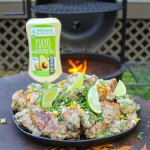 a plate of elote style chicken wings with a bottle of mayo in the background