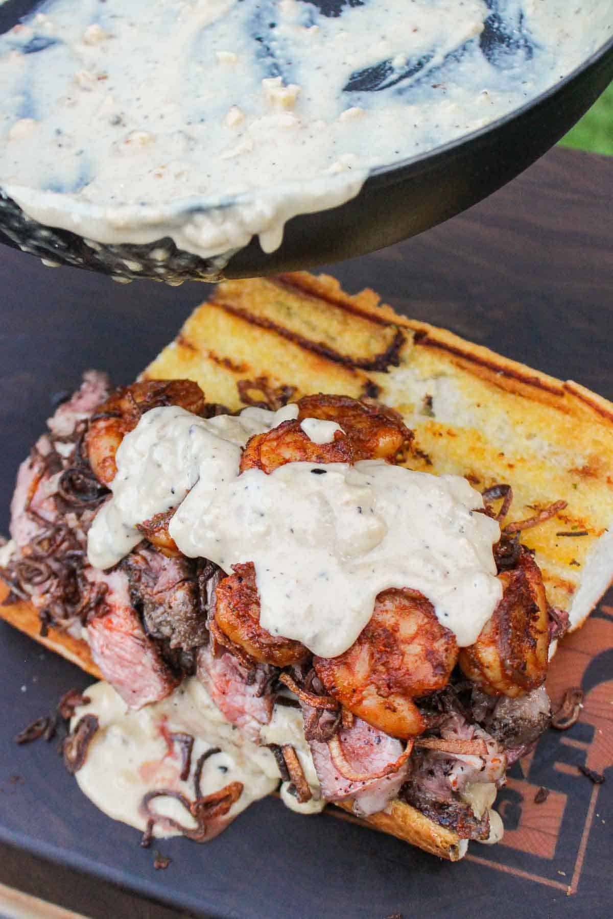 Adding the sauce to the surf and turf sandwich. 