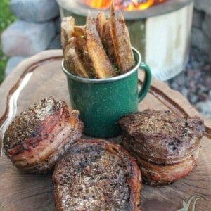 Bacon Wrapped Filets with Bacon Fat Fries sitting on a cutting board so that we can slice and serve them.