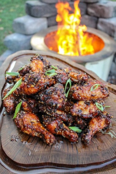 overhead of a platter filled with honey chili oil chicken wings next to a fire