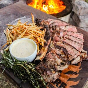 The grilled ribeye with beef tallow fries on a cutting board.