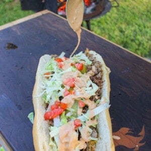 Animal Style Cheesesteak getting drizzled with the special sauce.