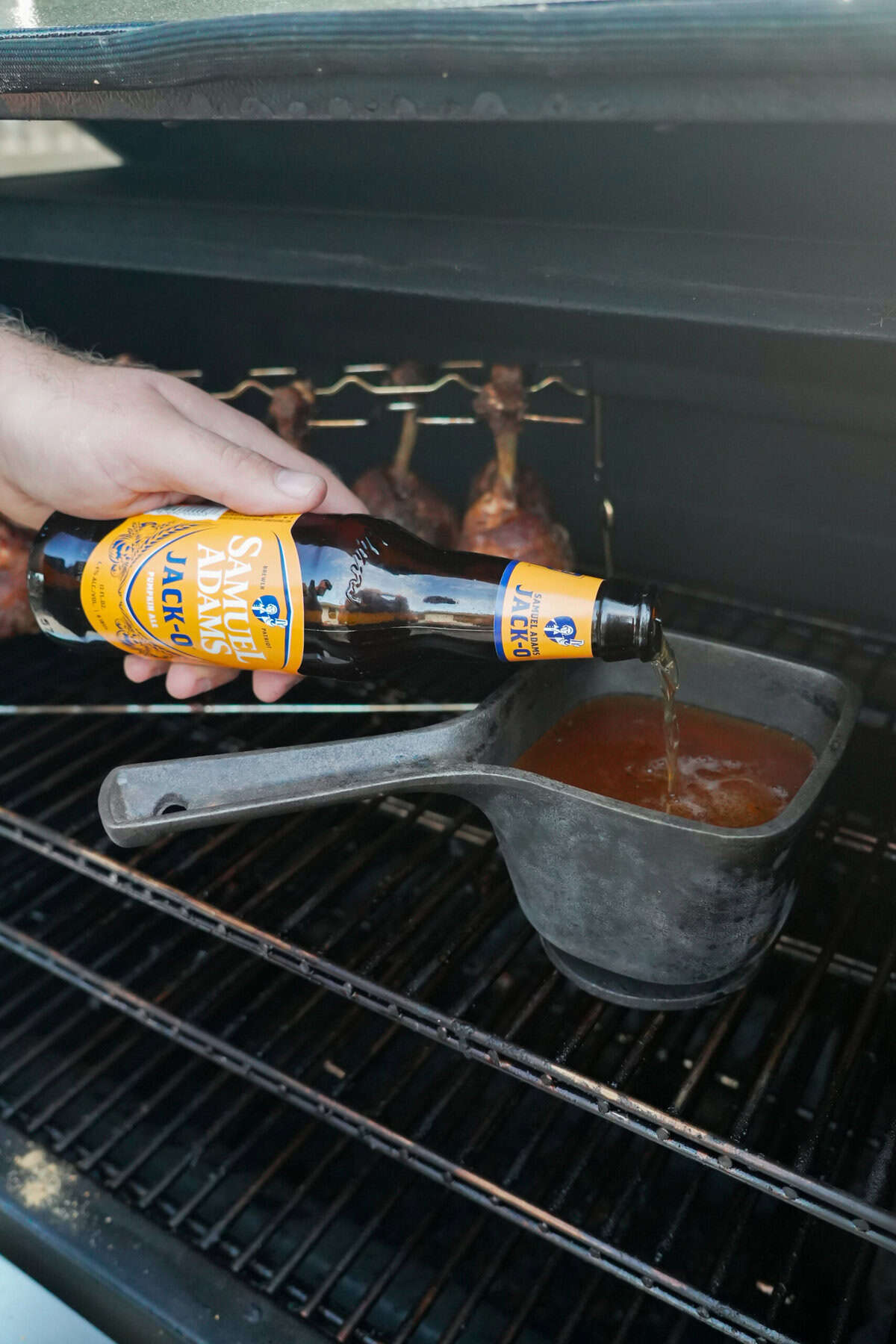 Pouring Samuel Adams Jack-O beer into a barbecue glaze in a saucepan on the grill