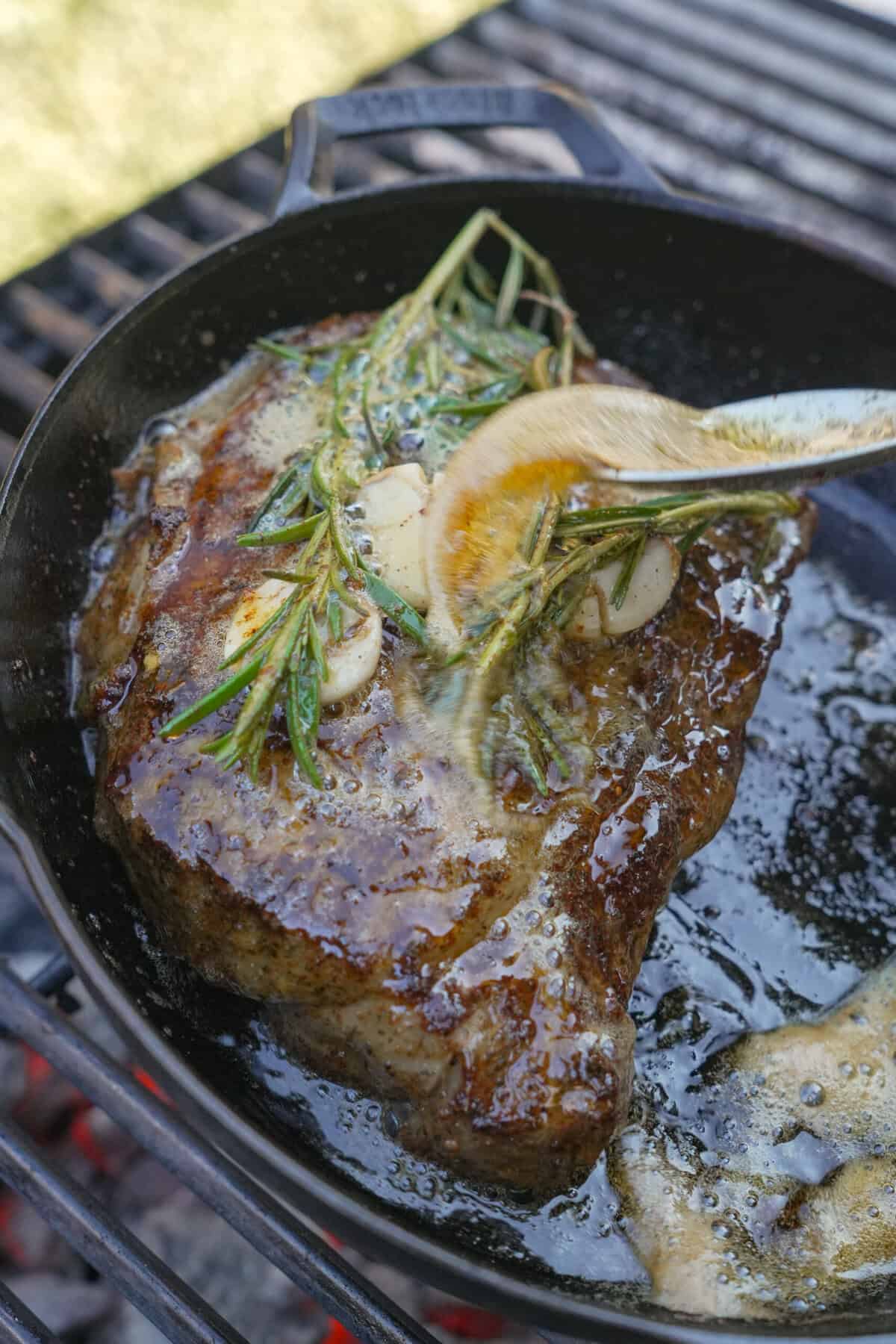 Ribeye steak sizzling in the cast iron pan with butter and fresh rosemary. It's a twist on the steak breakfast burrito that you won't want to miss. 