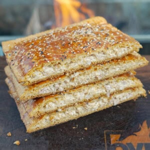 A stack of four chicken bacon ranch hot pockets coated with everything bagel seasoning with a grill fire in the background