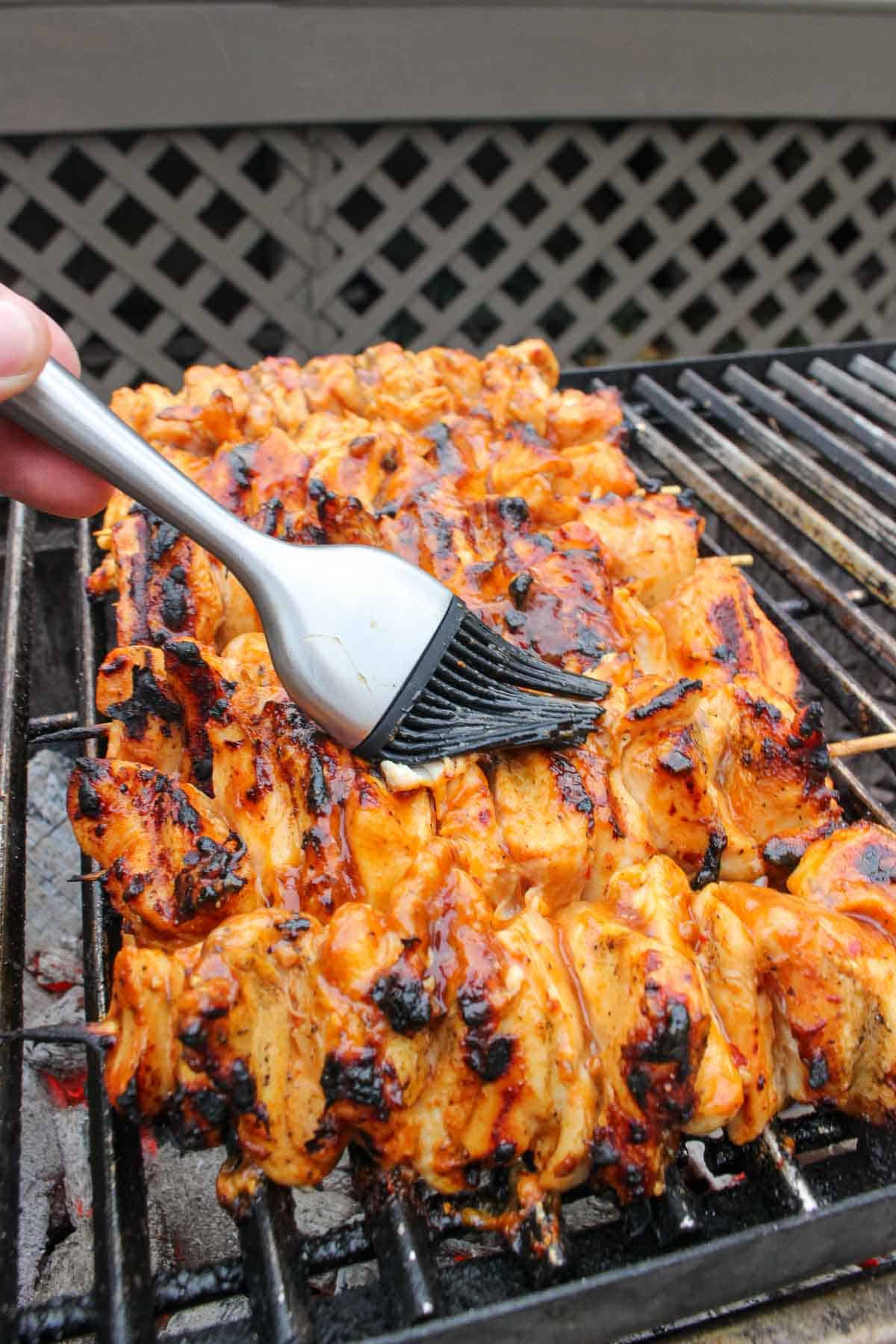 Basting the Hawaiian chicken skewers on the grill with a brush