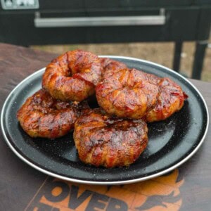 Several chorizo stuffed onion rings on a plate with a grill in the background