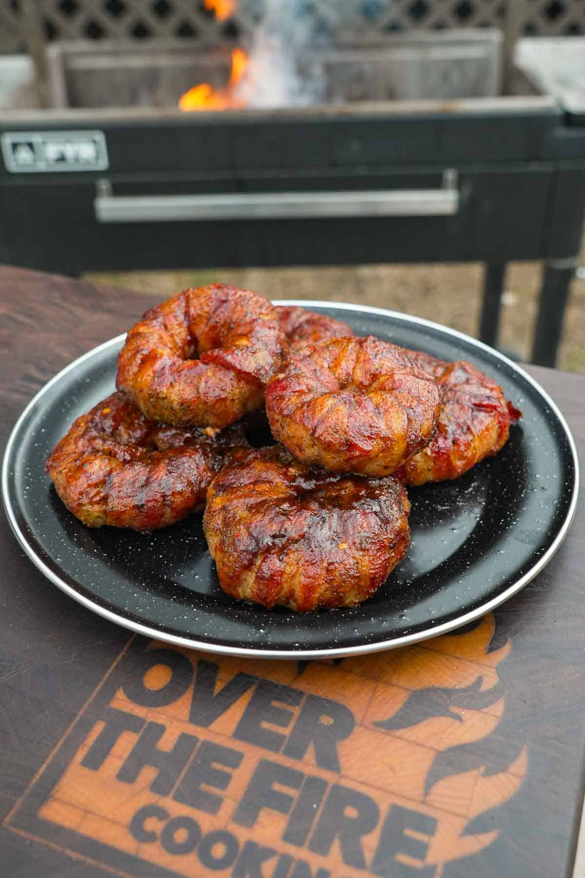Several chorizo stuffed onion rings on a plate with a grill in the background
