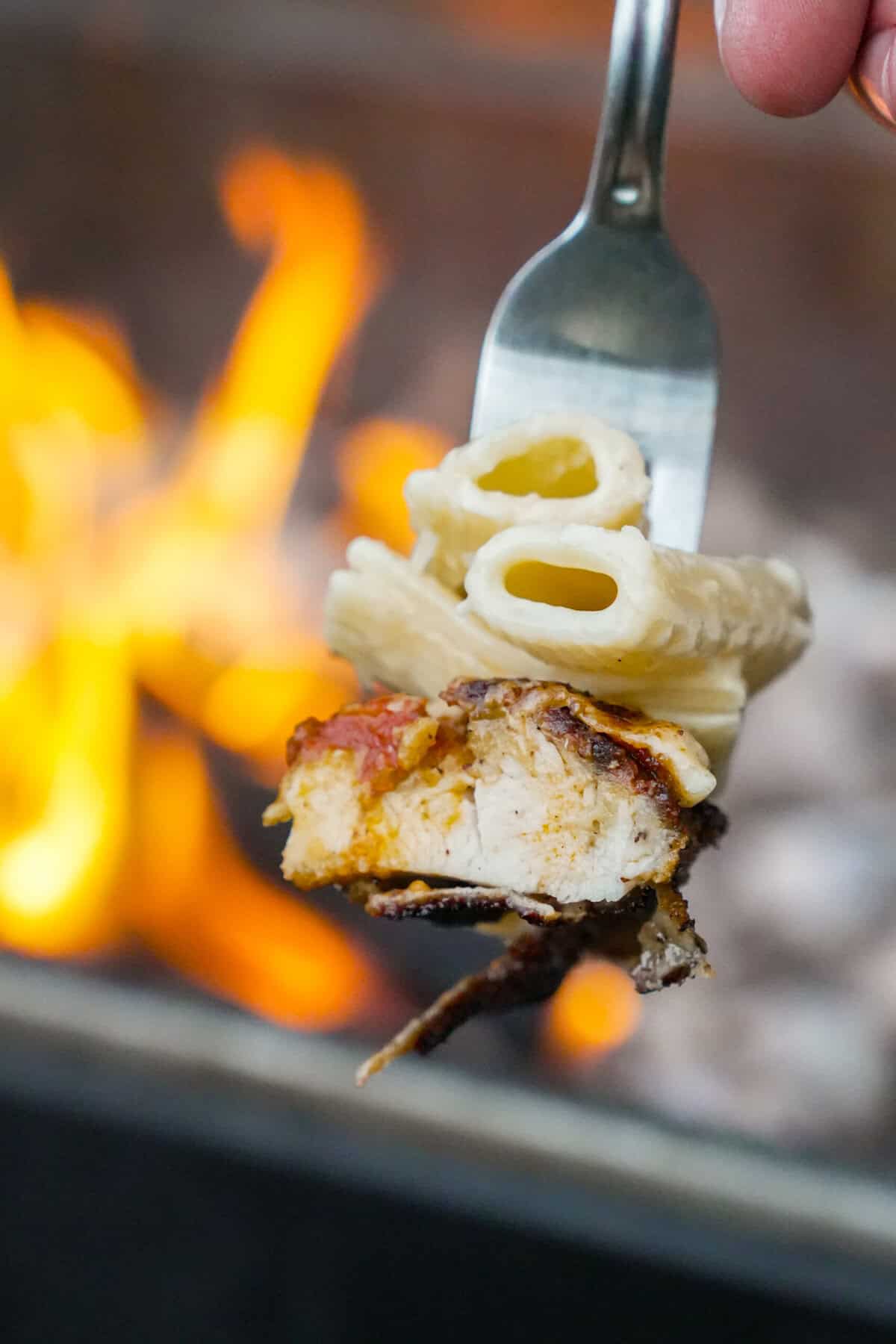 A close up of a forkful of rigatoni and breaded chicken