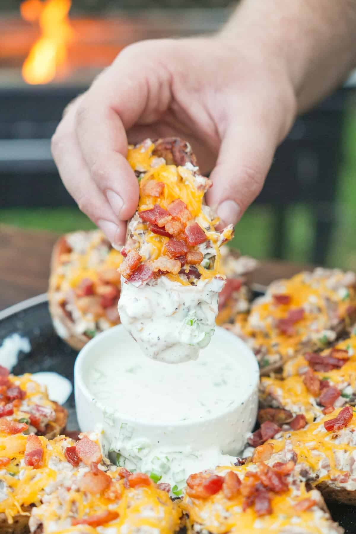 Dipping a loaded fried potato skin in jalapeño ranch dressing