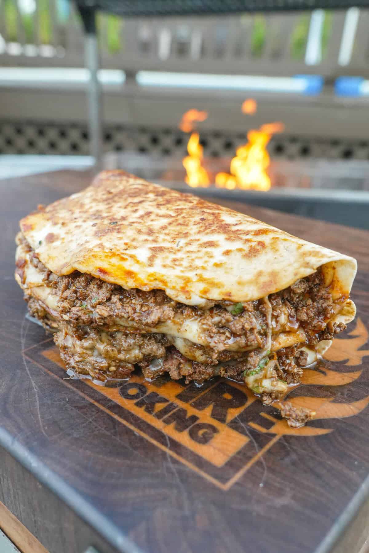 A close up of a finished loaded venison quesadilla with ground venison, mozzarella cheese, chipotle lime crema and a tortilla