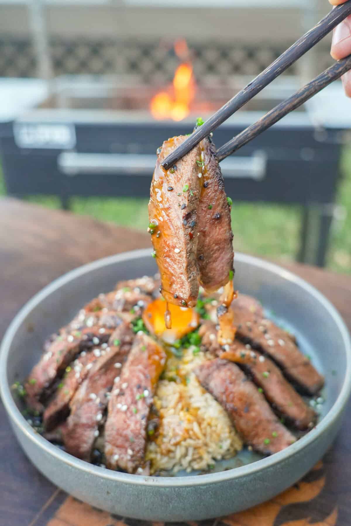A close up of the juicy steak slices after layering it over rice in the bowl.
