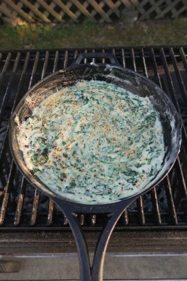 Cream spinach in a cast iron skillet on the grill