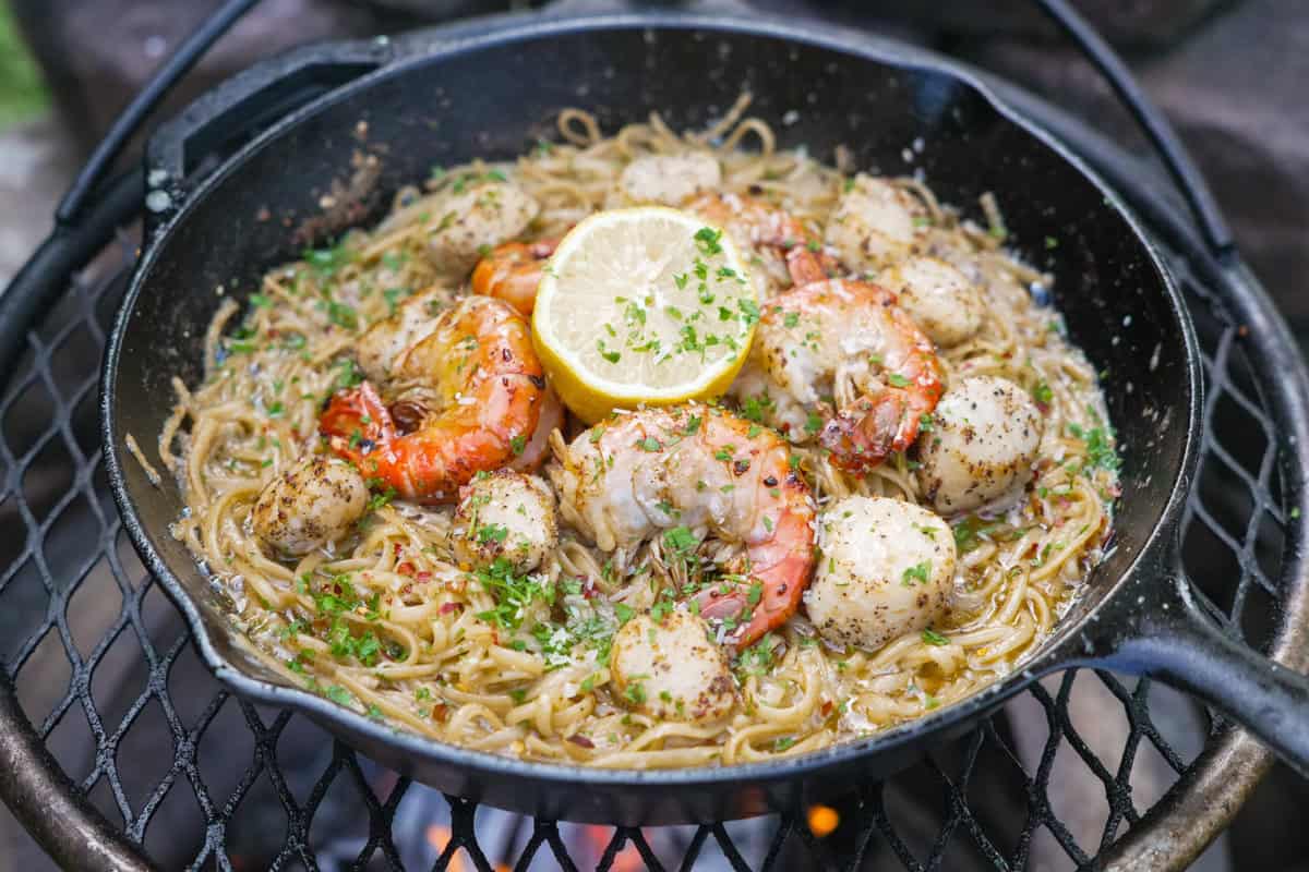 Seafood scamp in a cast iron skillet with spaghetti, shrimp, scallops, lemon and herbs