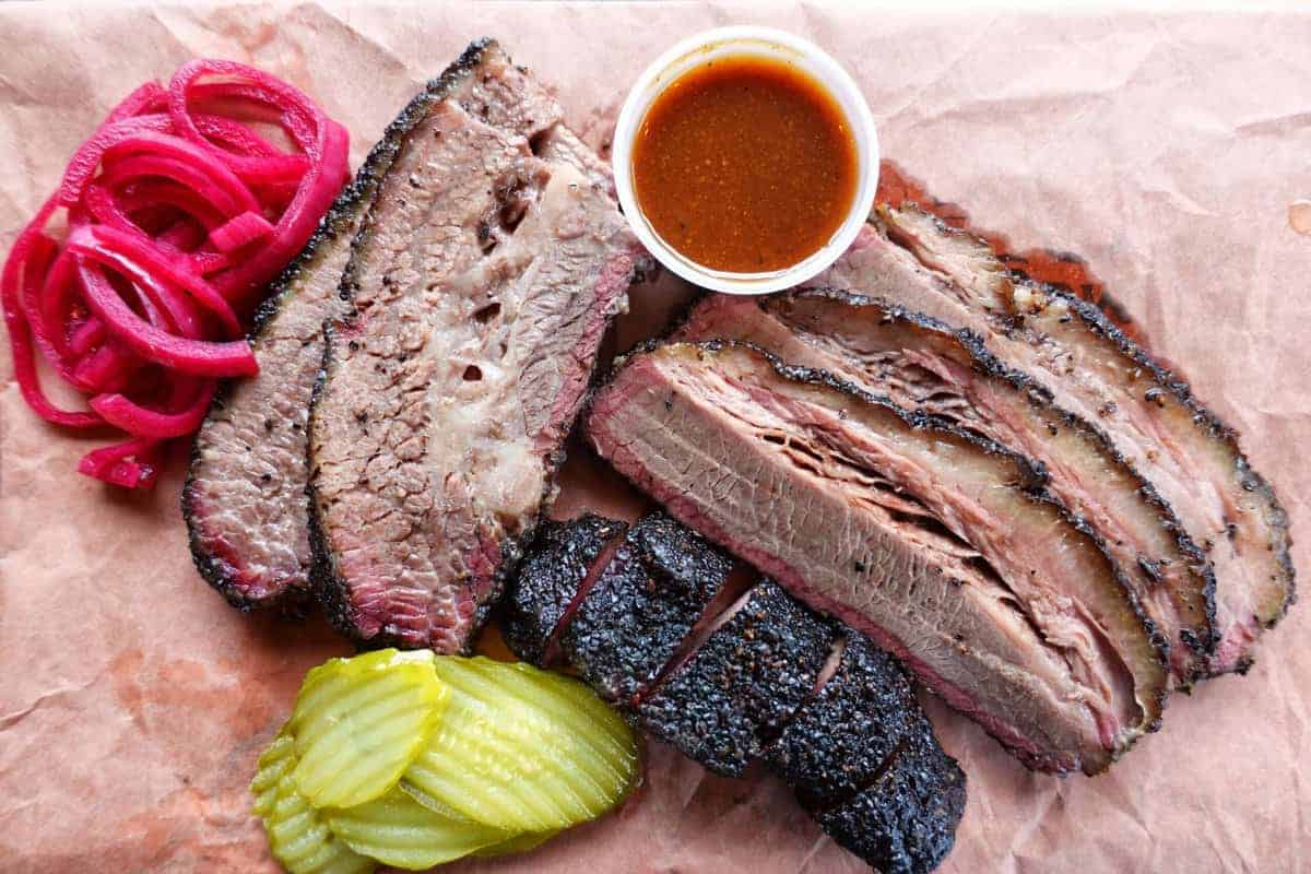 beef brisket is served with pickles and bbq sauce