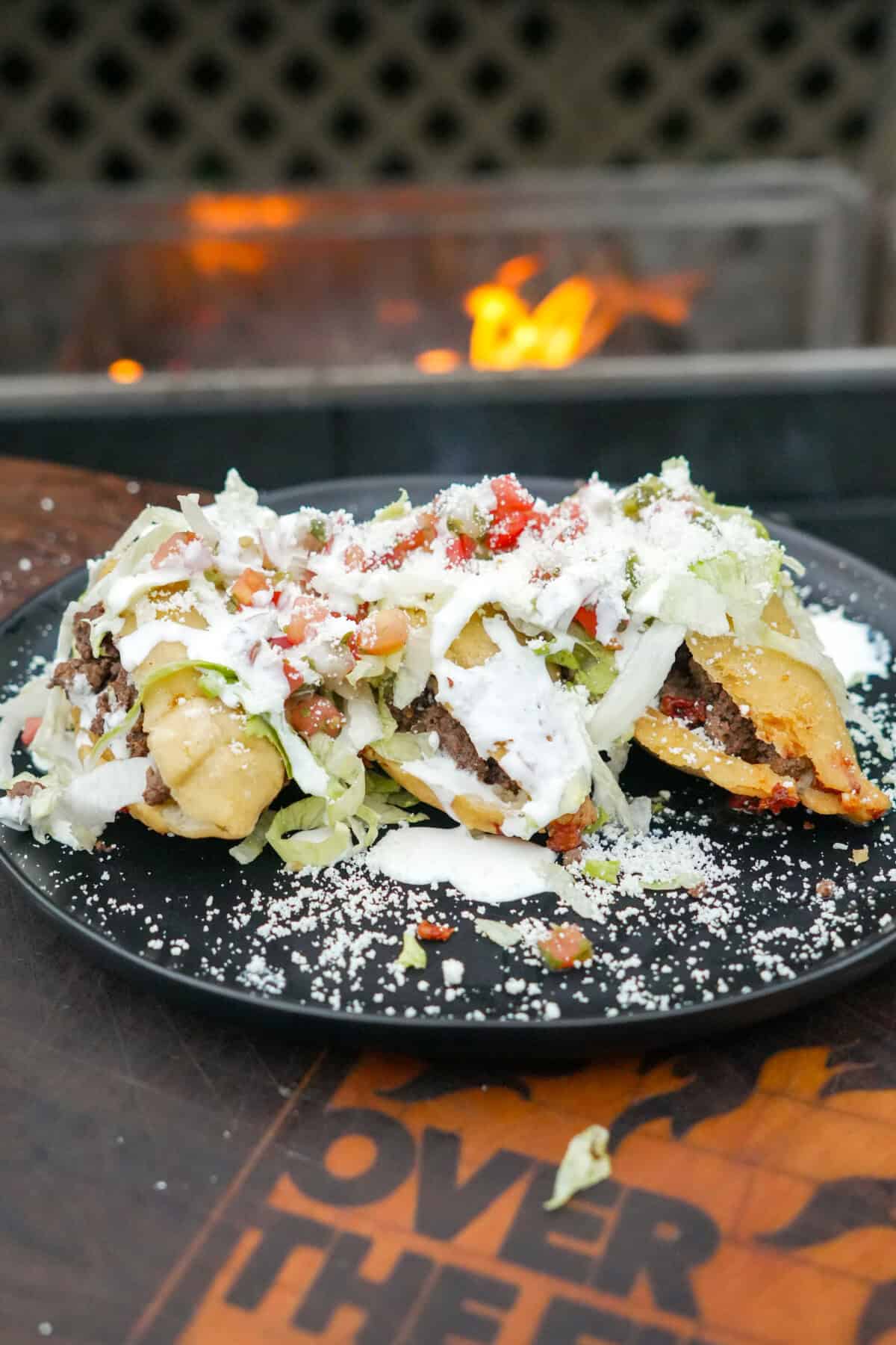 A side shot of fried quesadillas topped with shredded lettuce, pico de gallo, sour cream and cotija cheese