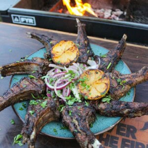 The grilled lamb chops are presented artistically on a plate with the onion salad in the center.