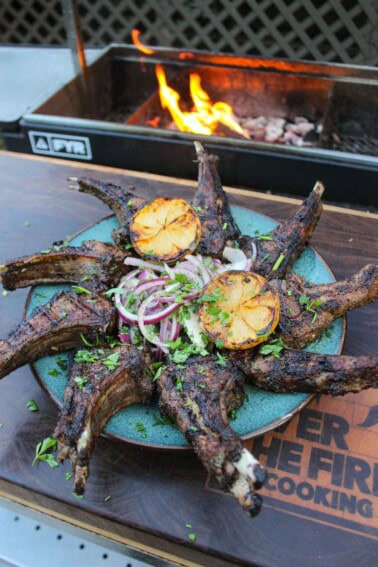 The grilled lamb chops are presented artistically on a plate with the onion salad in the center.
