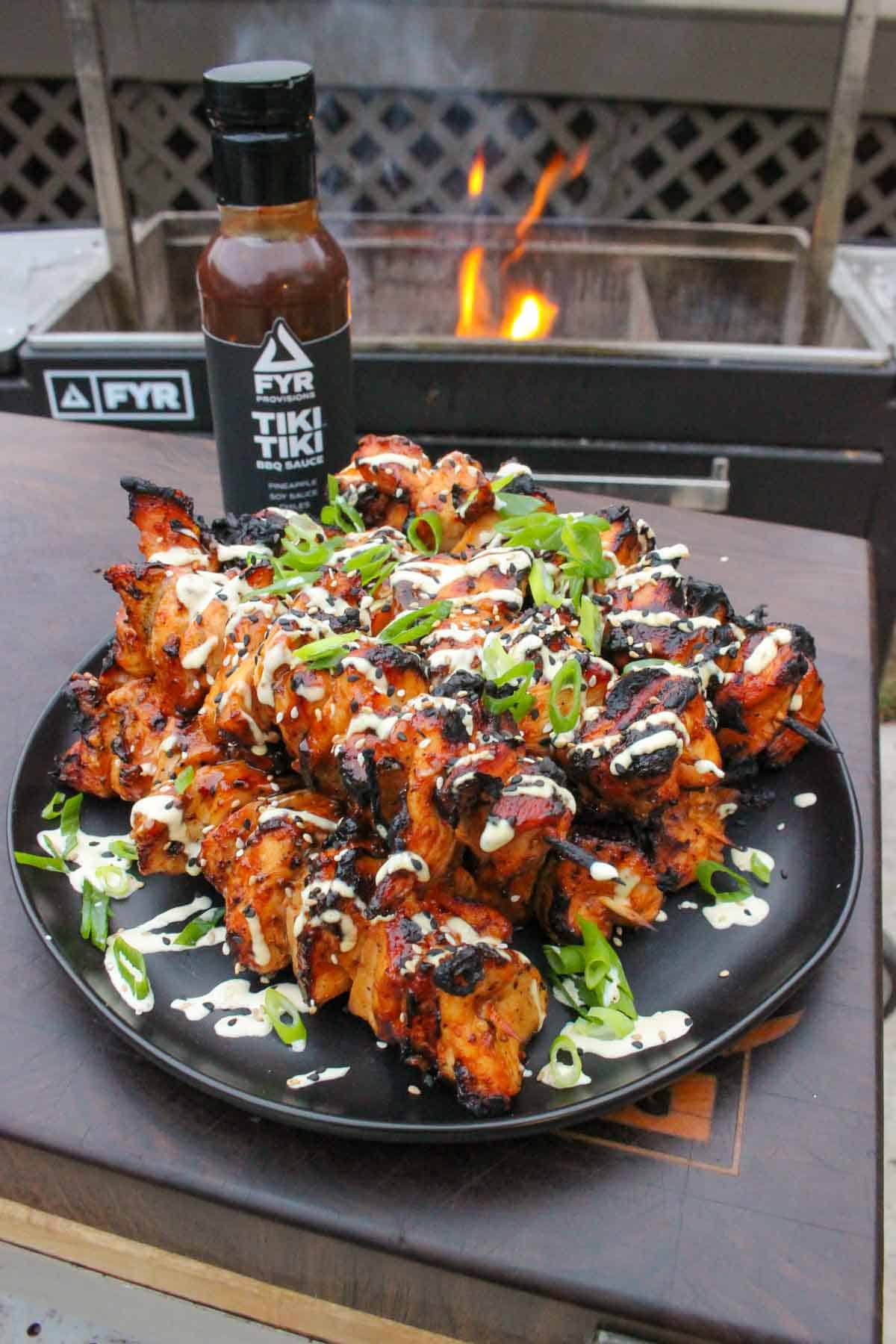 Hawaiian chicken skewers on a plate with Tiki Tiki BBQ Sauce in the background