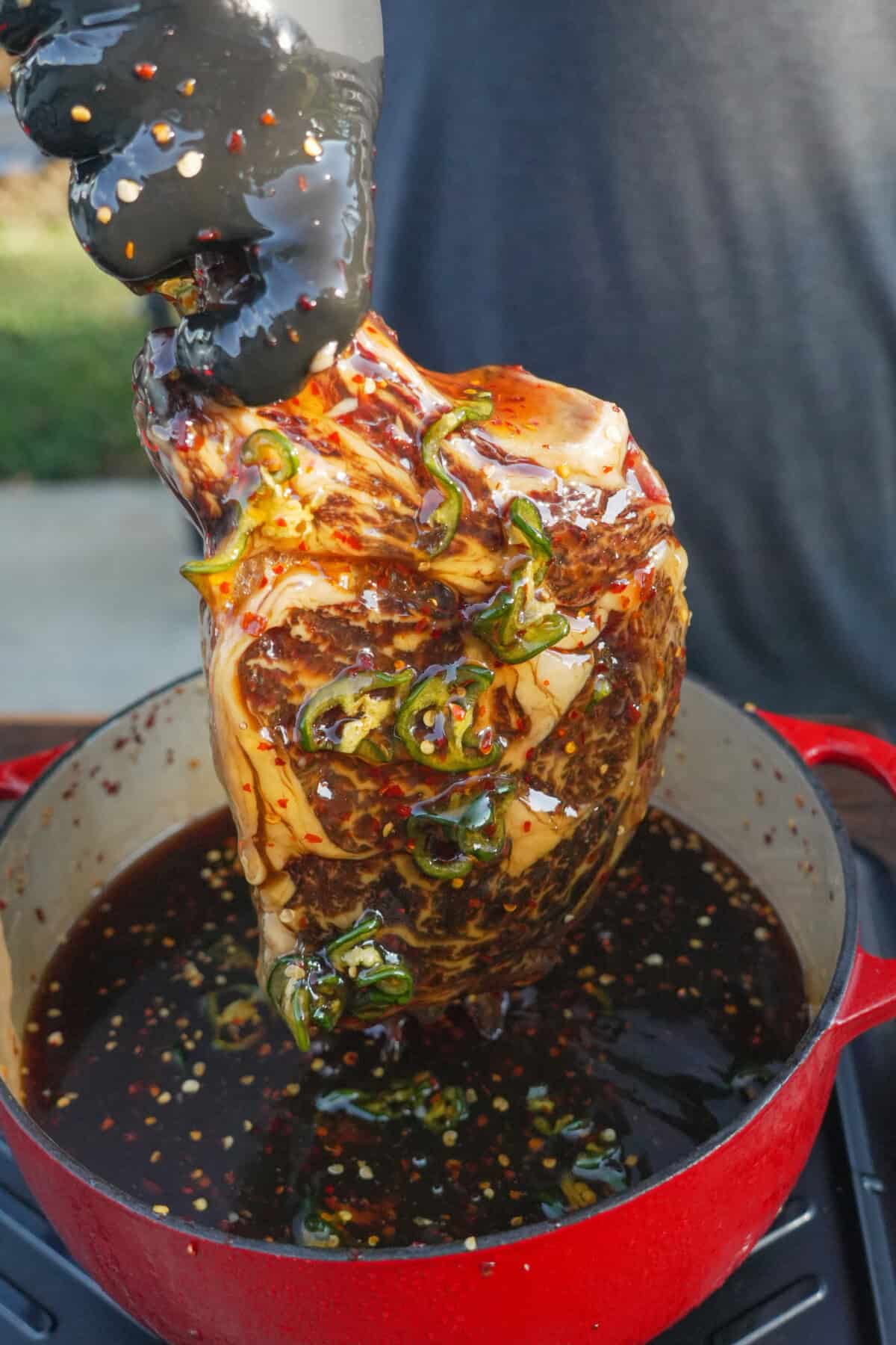 Close up of steak being pulled out of the honey and jalapeno cure.