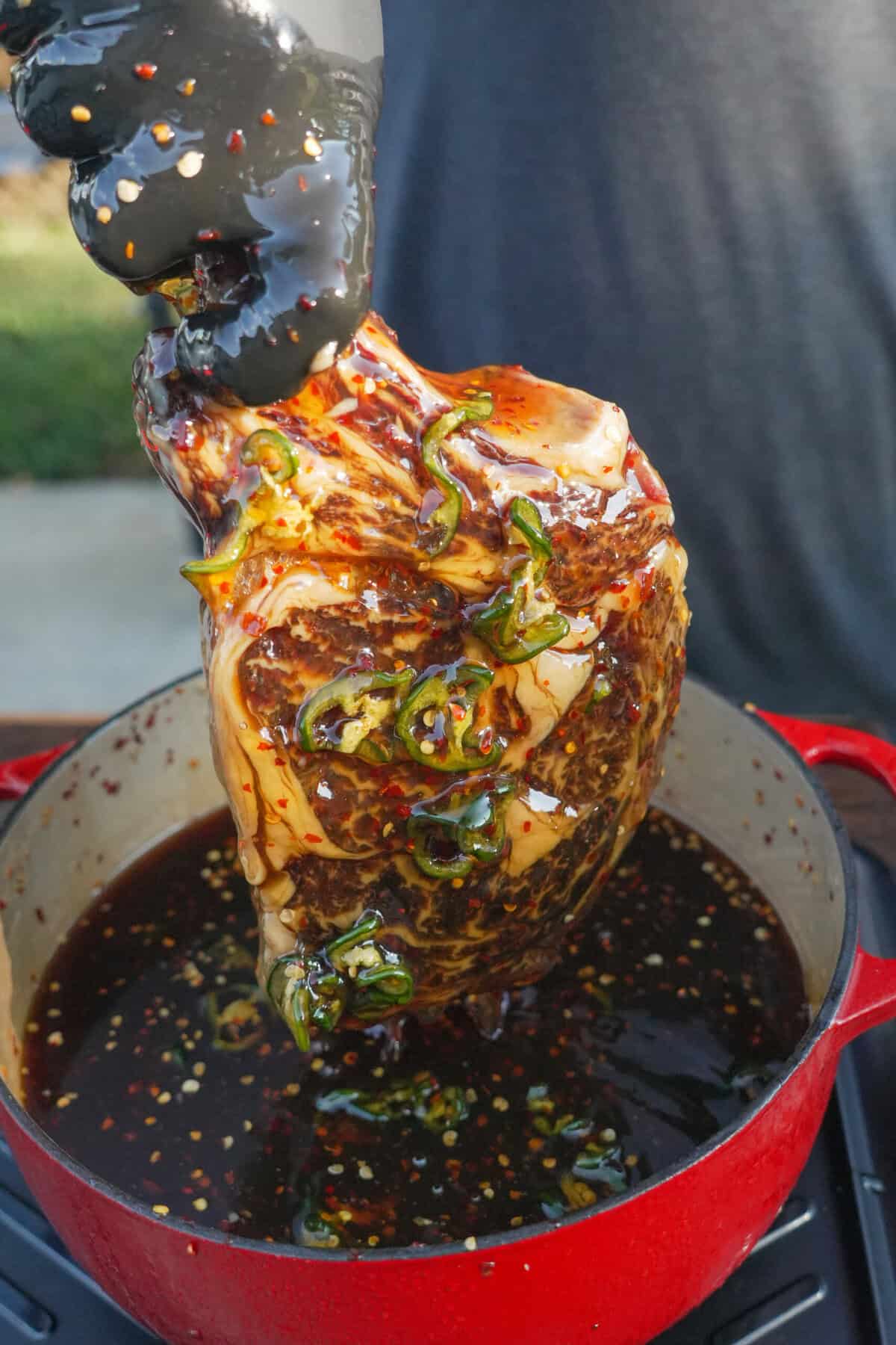 Close up of steak being pulled out of the honey and jalapeno cure. 