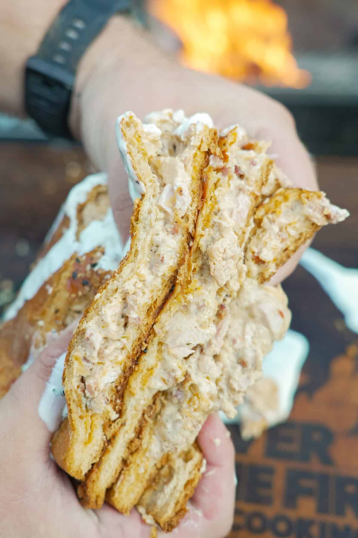 Hands holding a sliced open chicken bacon ranch hot pocket to show the filling