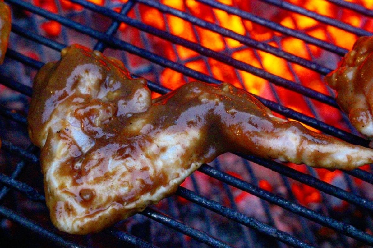 Coca Cola wings getting starting on the grill over some hot coals.