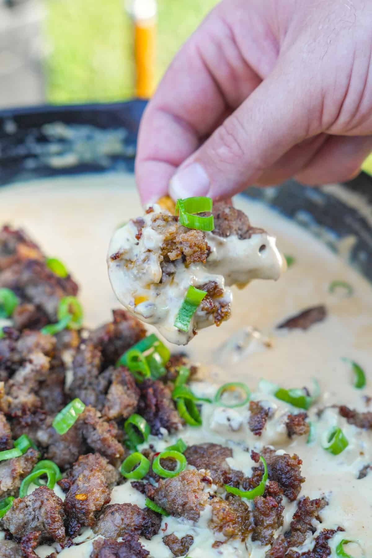 A close up image of the beer dip showing the gooey cheese, sausage, and green onions.