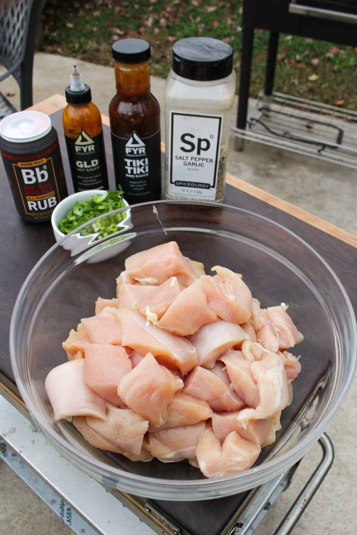 Chicken cubed in a bowl with scallions, Tiki Tiki BBQ Sauce, spice rub, sesame seeds