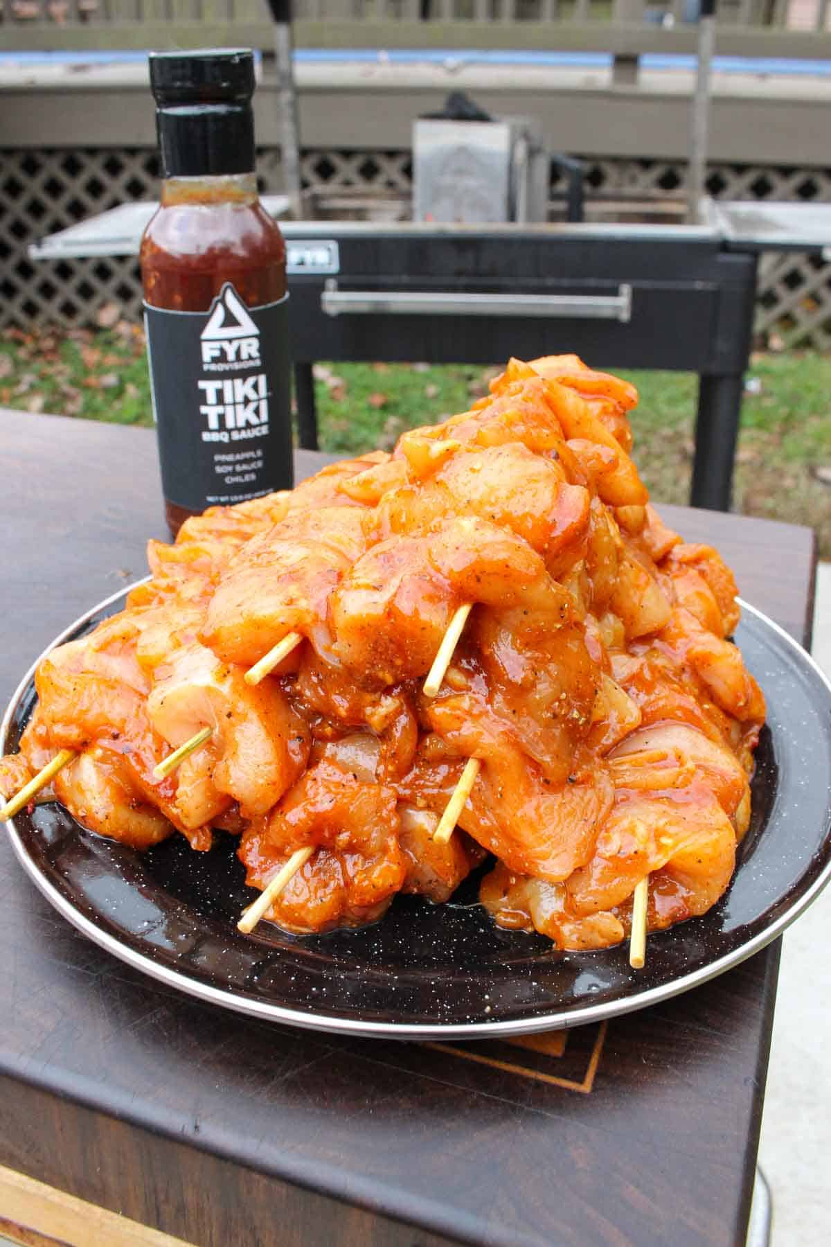 Prepared Hawaiian chicken skewers on a plate with Tiki Tiki BBQ Sauce in the background