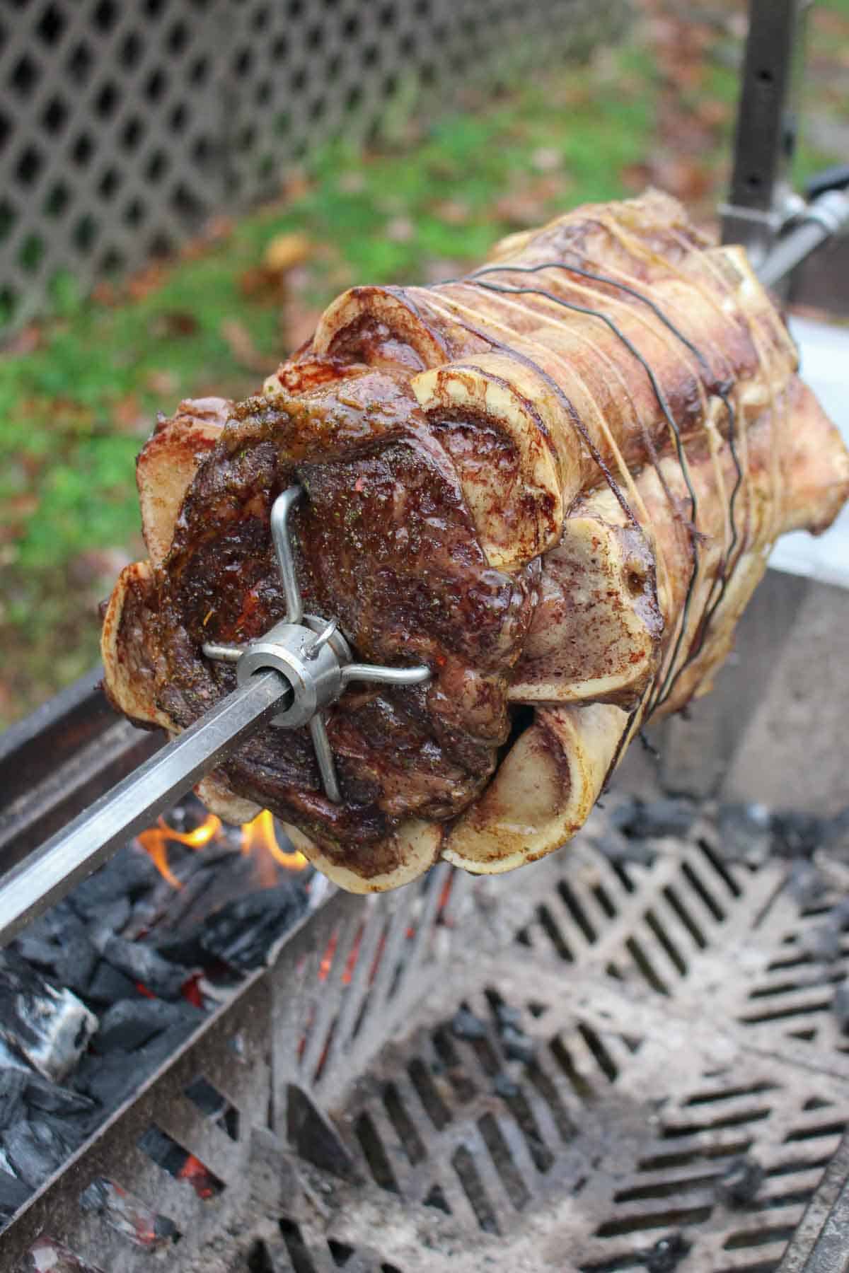 A prime rib roast on a rotisserie attachment over the FYR Grill
