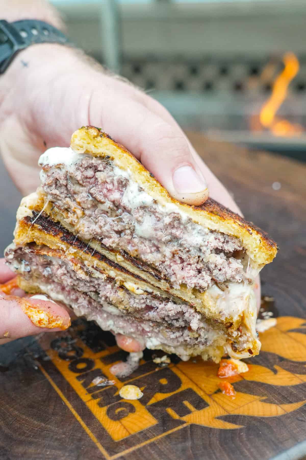 A sliced open pizza smashburger to show the beef patties, mozzarella cheese, pizza sauce and garlic aioli