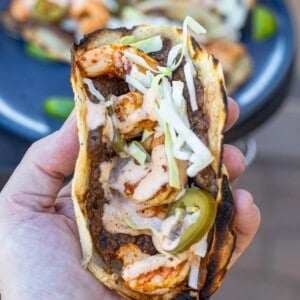 A Surf and Turf Smashburger Taco being held up close to the camera so you can see it's different ingredients.