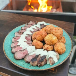 A platter of grilled New York strip steak with jalapeño popper croquettes and avocado ranch dressing in between them