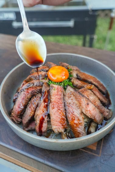 The umami sauce is drizzled over our ribeye steak slices laying artfully over a bed of rice with an egg yolk in the center.