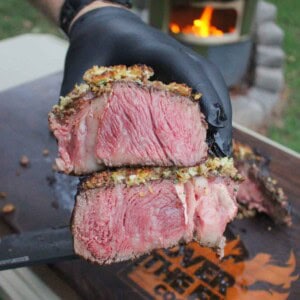Cutting Board Care: A gloved hand holding a crusted tomahawk steak sliced open to reveal the delicious crust and the juicy interior of the meat