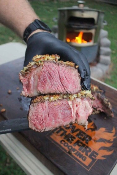 Cutting Board Care: A gloved hand holding a crusted tomahawk steak sliced open to reveal the delicious crust and the juicy interior of the meat
