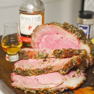 The perfectly cooked Whisky Injected Prime Rib is displayed on the cutting board in front of a bottle of Pendleton Whisky.
