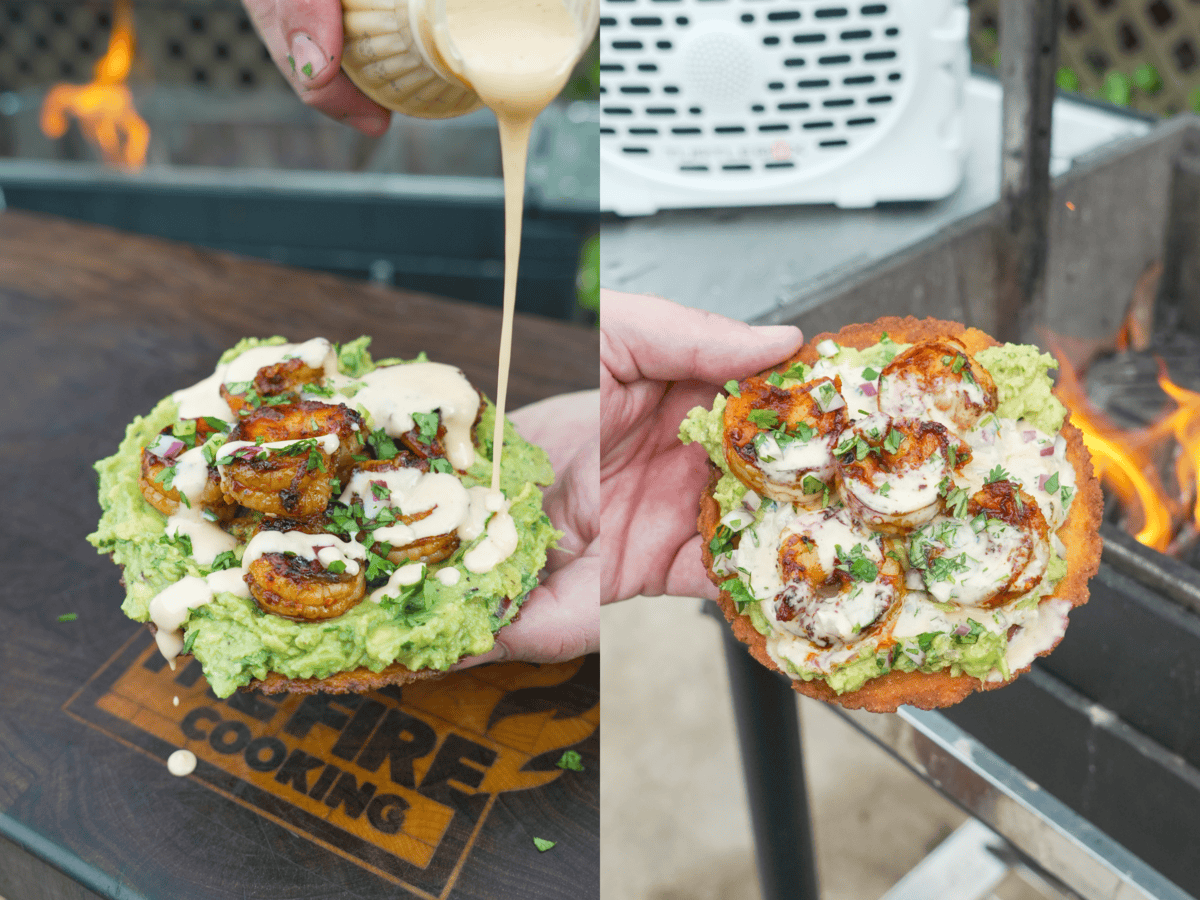 A hand holding an assembled shrimp tostada and pouring sauce over it from a mason jar