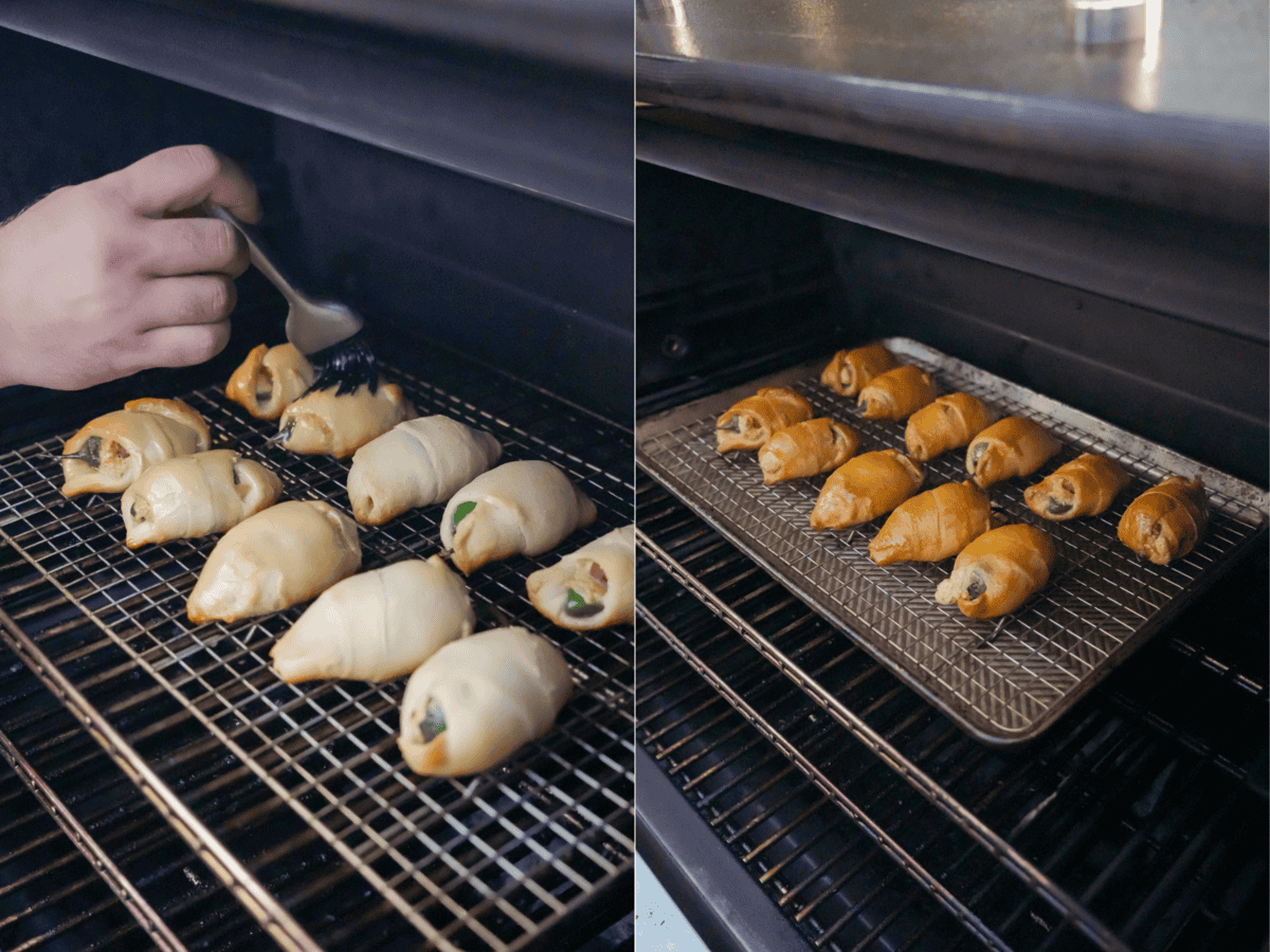 A hand holding a grill brush and brushing honey butter on jalapeño popper pigs in a blanket while they're smoking on the grill, then showing them in progress with golden brown crescent roll dough