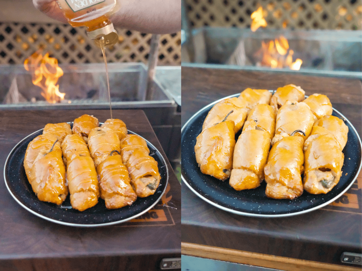Drizzling honey butter out of a squeeze bottle on a plate of finished jalapeño popper pigs in a blanket, then showing the finished platter