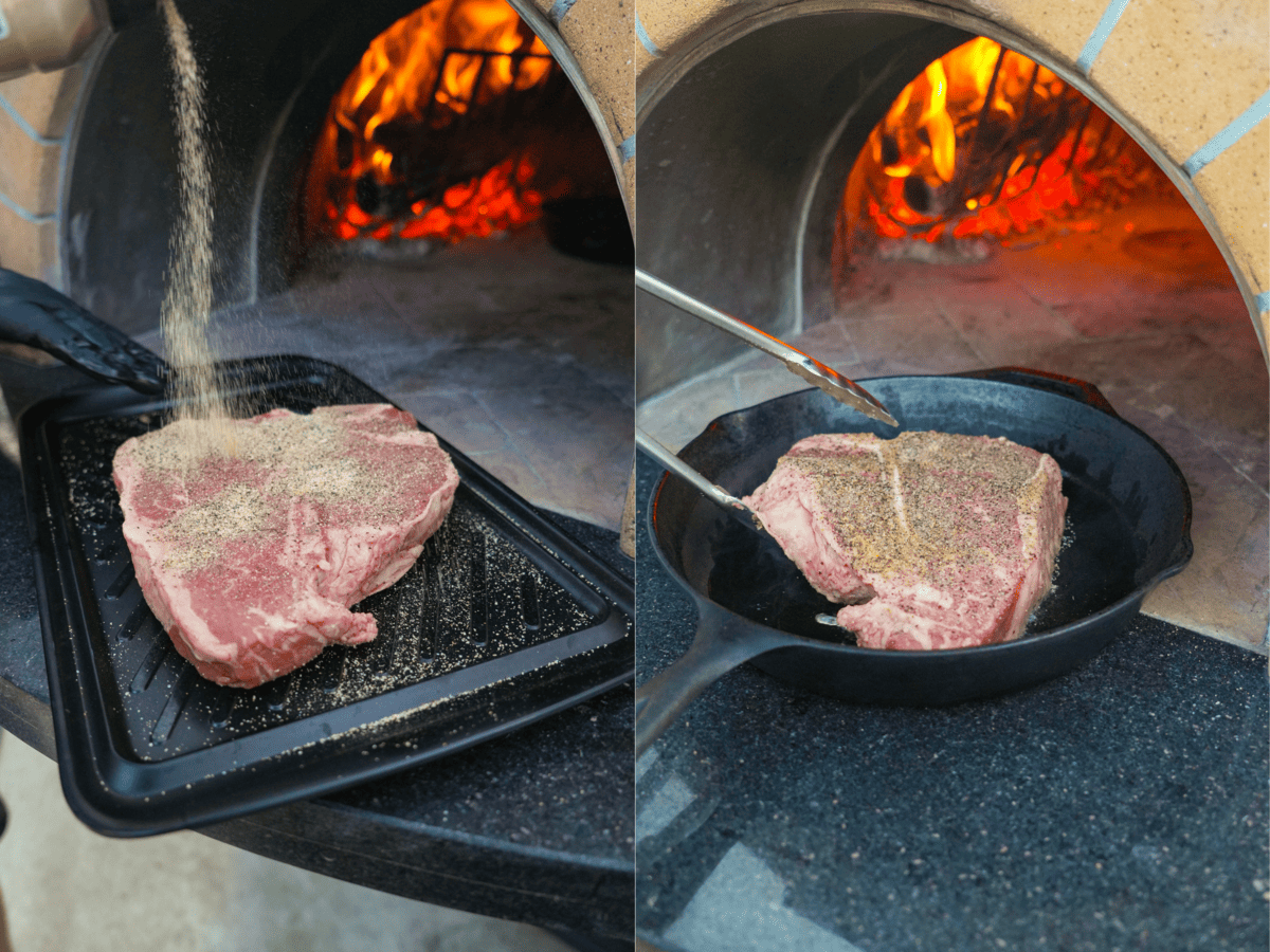 Raw T-bone steak being seasoned with salt and pepper before searing in a hot skillet by the fire.
